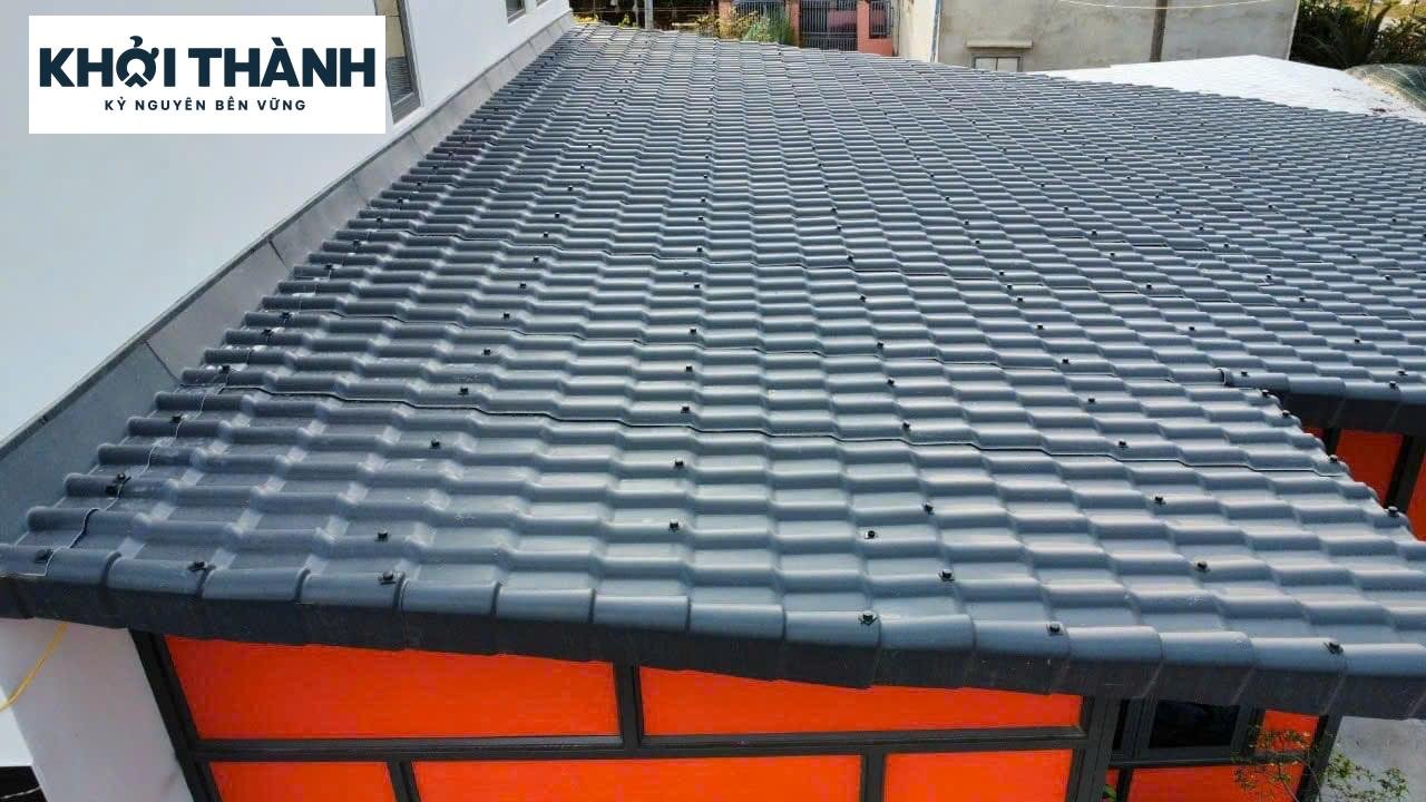 Mái ngói nhựa xám phủ khu vực hiên cạnh tường nhà.